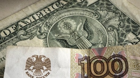 Un billet de cent roubles devant un billet d'un dollar américain (image d'illustration).