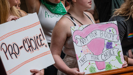 Une militante pour le droit à l'avortement tient une pancarte à côté d'une militante anti-avortement dans le bâtiment du Capitole de l'Indiana, le 25 juillet 2022