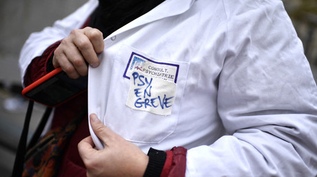 Un psychiatre affiche un slogan «en grève» alors que ses collègues se rassemblent devant le ministère de la Santé le 29 novembre 2022 pour dénoncer la «situation alarmante de la psychiatrie publique».