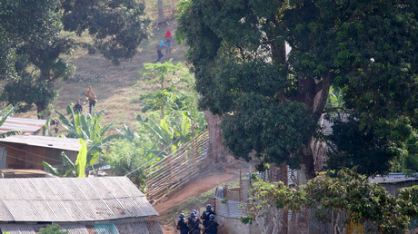 Des forces de police, dont l'unité du RAID, se mettent à l'abri face à des émeutiers  le 28 novembre 2022 dans le village de Vahibe, au nord de Mayotte.