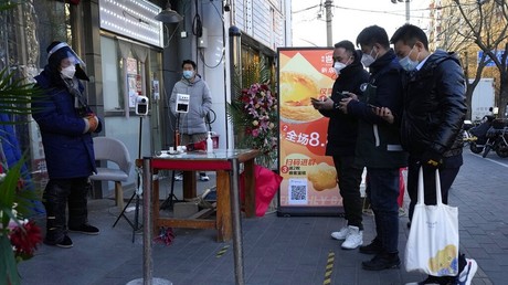 Des habitants s'apprêtent à présenter leur pass sanitaire à l'entrée d'un marché qui rouvre ses portes à Pékin, le 3 décembre 2022, sur fond d'assouplissement des restrictions dans plusieurs villes (image d'illustration).