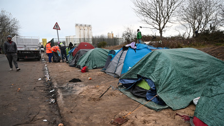 Des migrants marchent à côté de tentes de fortune installées dans un camp à Calais, le 26 novembre 2019 (image d'illustration).