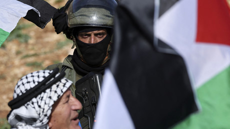 Un soldat israélien regarde un Palestinien agiter un drapeau lors d'une manifestation contre l'établissement de colonies israéliennes, à Beit Dajan, à l'Est de la ville occupée de Naplouse en Cisjordanie, le 10 février 2023.