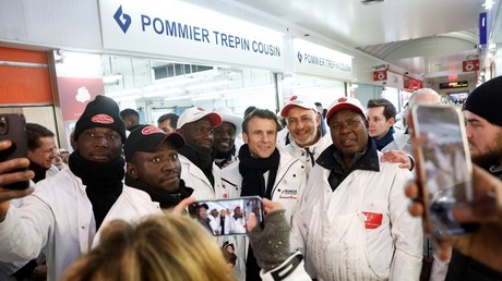 Le président français Emmanuel Macron (au centre) pose pour une photo avec des ouvriers lors d'une visite au Marché international de Rungis, à Rungis (Val-de-Marne), dans la banlieue sud de Paris, le 21 février 2023.