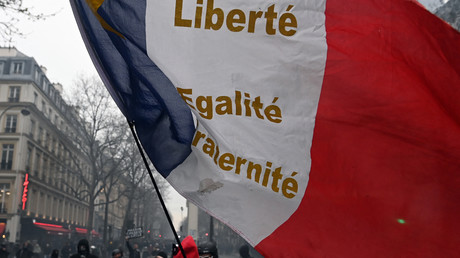 Un homme tient un drapeau français lors d'une manifestation contre la réforme des retraites, à Paris le 23 mars 2023.