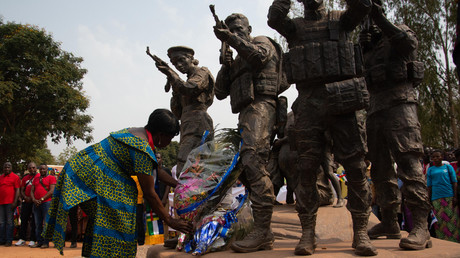 A l'occasion d'une manifestation pour remercier les Russes de les avoir débarrassés des rebelles le 23 février 2022 à Bangui, une femme dépose une gerbe de fleurs au pied d'un monument représentant des soldats centrafricains et des Russes armés protégeant une femme et ses enfants.