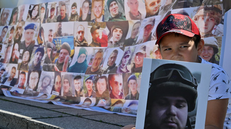 Jeune garçon ukrainien tenant la photo de son frère, lors d'une manifestation réclamant le retour des prisonniers de guerre à Kiev, juillet 2023.