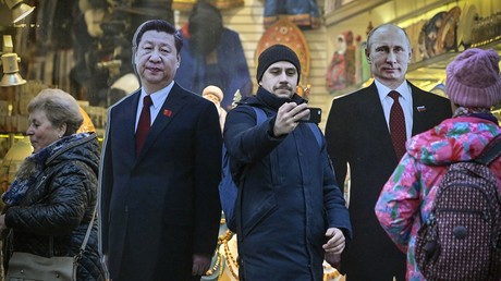 Touristes se prenant en photo rue Arbat à Moscou devant des effigies des dirigeants russe et chinois (image d'illustration).