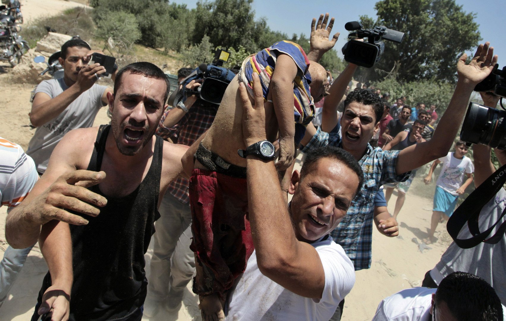 شبان يحملون طفلاً قتل في القصف الإسرائيلي لمدينة غزة في 9 يوليو