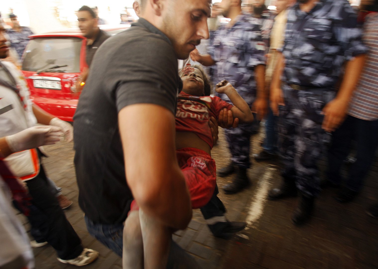 رجل يحمل فتاة فلسطينية أصيبت خلال القصف الإسرائيلي على منزل في غزة، 9 يوليو