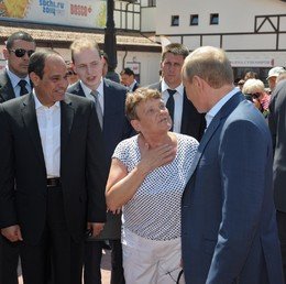 الرئيس بوتين يخاطب إمرأة محلية أثناء التنزه مع الرئيس السيسي في شارع بلدة روزا خوتور 12 أغسطس/آب.