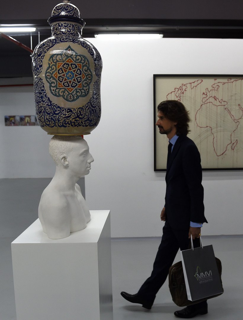 رجل يسير أمام تمثال لمهدي جورج لحلو 