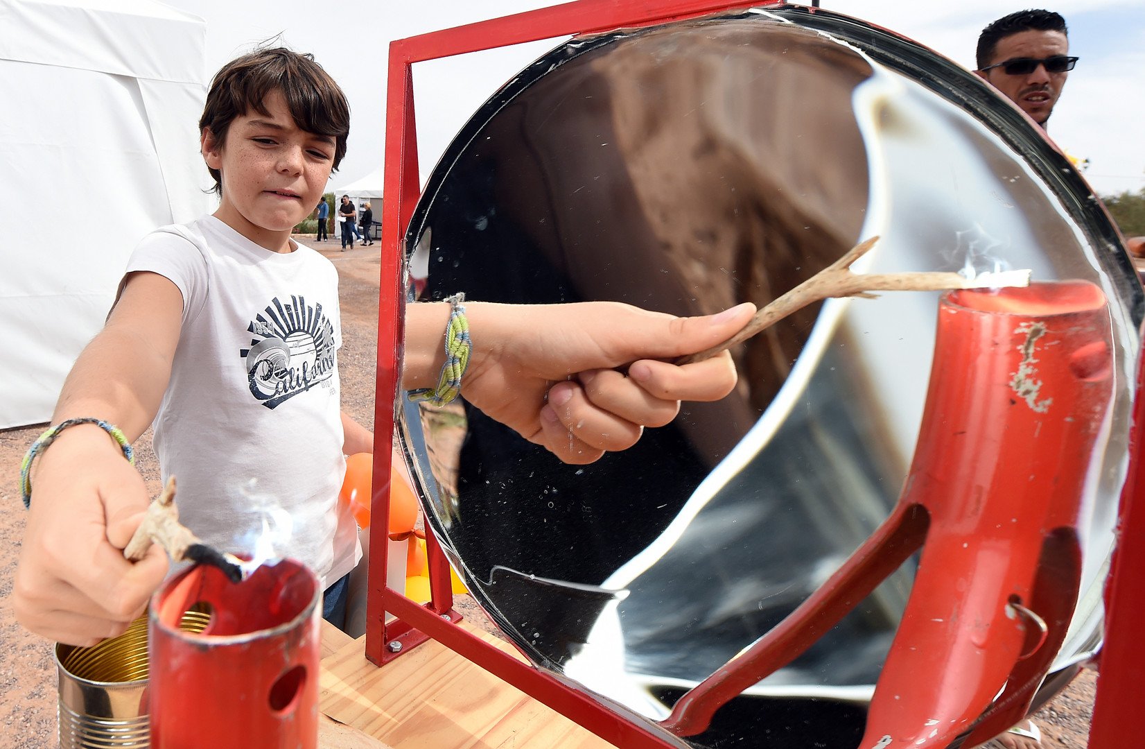 طفل يحرق فرع شجرة باستخدام انعكاس أشعة الشمس خلال مهرجان المغرب للطاقة الشمسية