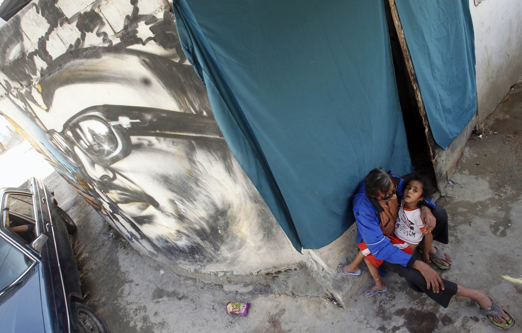 فلسطيني يحمل طفلا بجانب صورة للزعيم الفلسطيني ياسرعرفات في مخيم للاجئين الفلسطينيين جنوب لبنان  