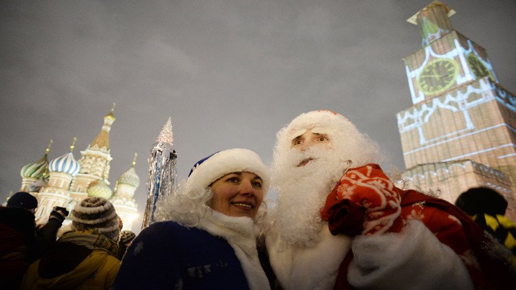 رجل يرتدي زي بابا نويل برفقة فتاة خلال الاحتفال في الساحة الحمراء وسط وسكو