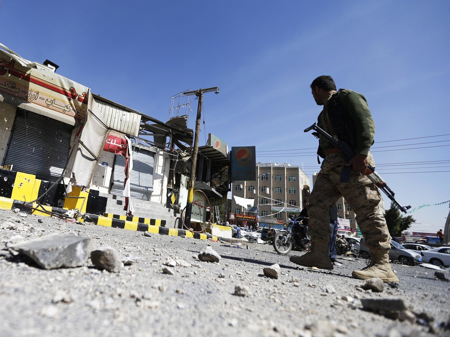 مقاتل حوثي يتفقد بعض المحلات التي تضررت إثر الاشتباكات مع الحرس الرئاسي