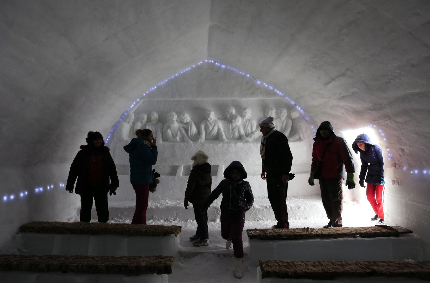 سائحون يتجولون داخل الكنيسة أمام لوحة منحوته في الجليد تصور مشهد العشاء الأخير، 28 يناير 2015