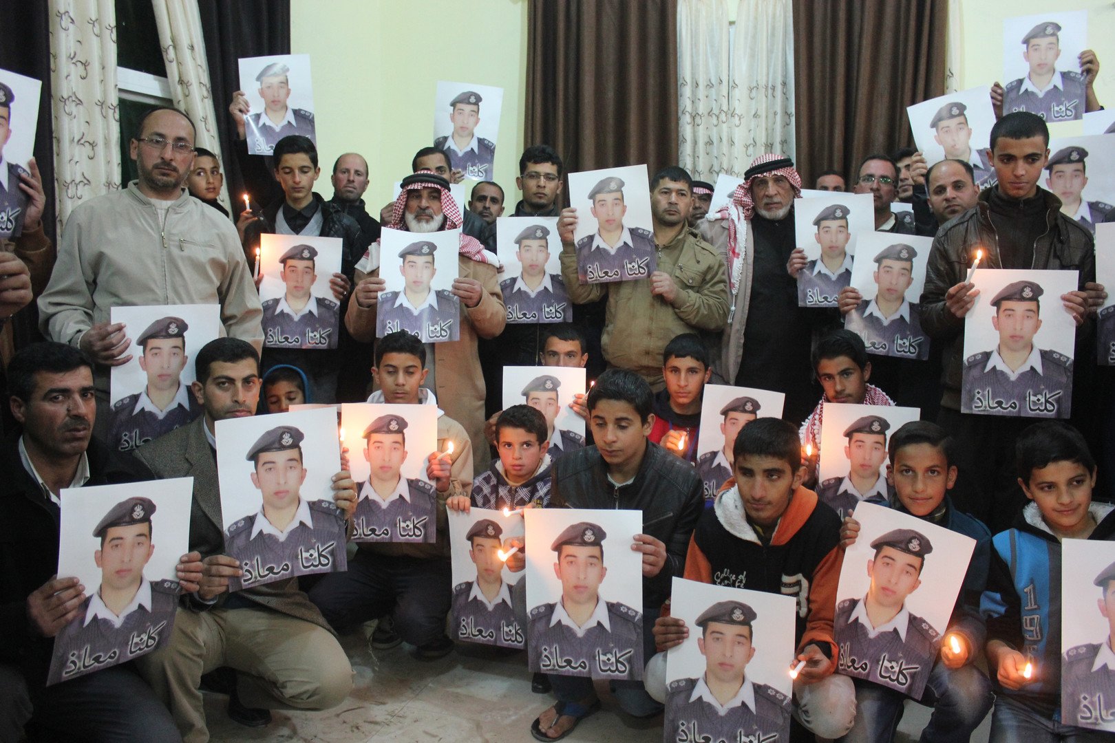  أقارب الطيار معاذ الكساسبة يحملون صورا له خلال مسيرة في مدينة الكرك، مقر أسرته، 31 يناير 2015 