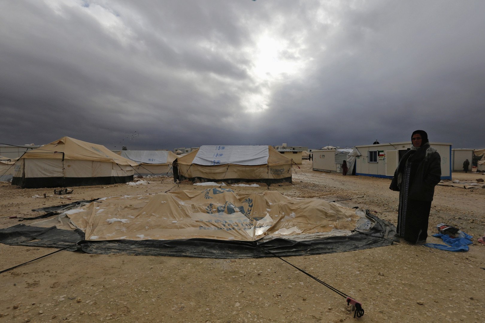 سيدة تقف أمام خيمتها التي أسقطتها عاصفة ثلجية داخل مخيم الزعتري، 8 يناير 2015 