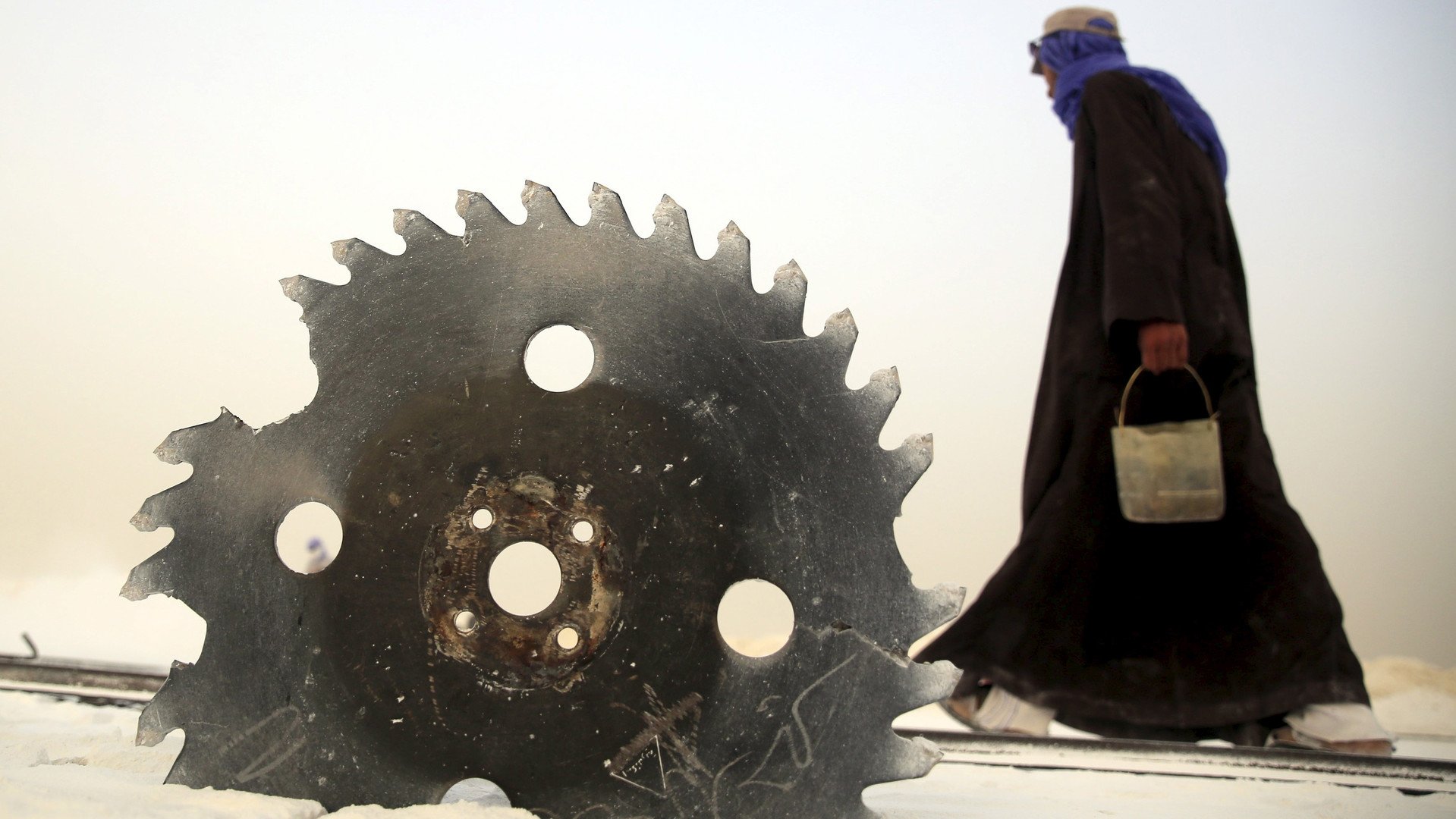 عامل يسير بجانب آلة قطع الحجر الجيري في محاجر المنيا بصعيد مصر، 28 مايو 2015