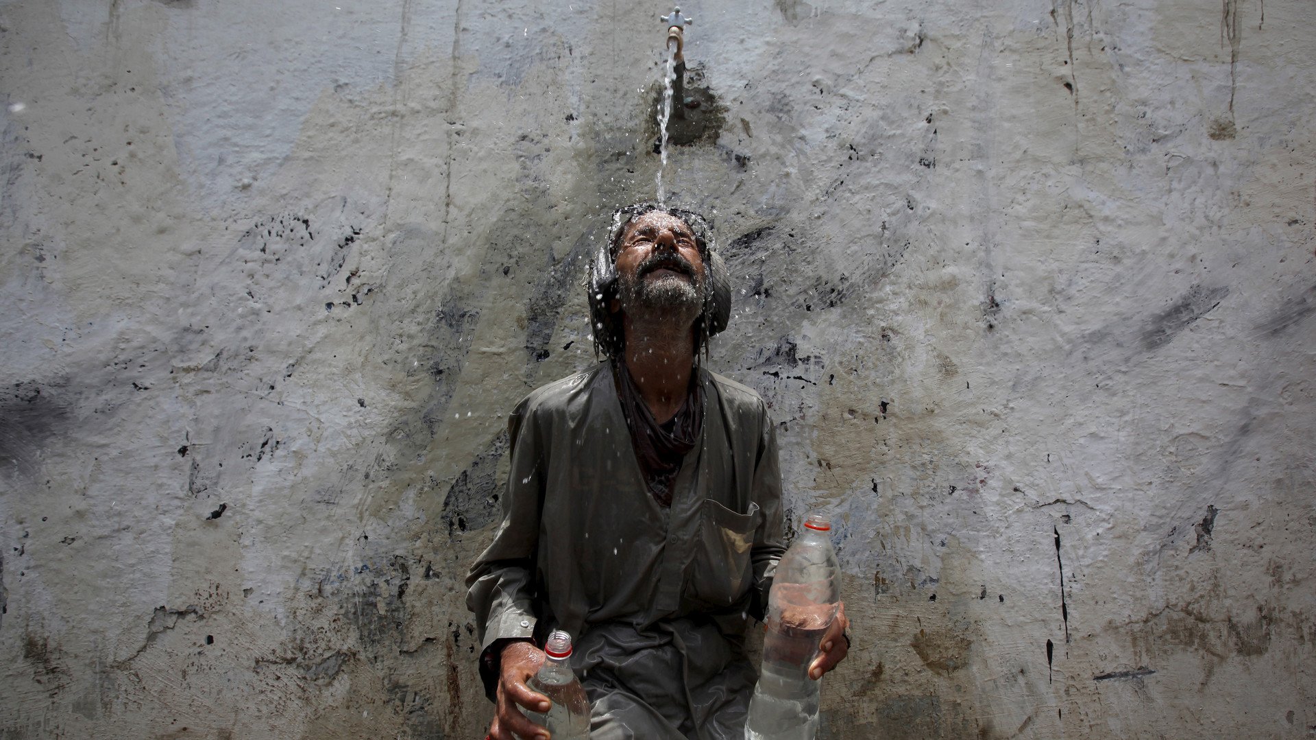 رجل يخفف وطأة الحر عليه بمياه صنبور عمومي ، كراتشي، 23 يونيو/حزيران