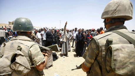 الجنود الأتراك يحرسون الحدود بينما ينتظر السوريون لوسائل تنقلهم إلى داخل تركيا، 10 يونيو 2015
