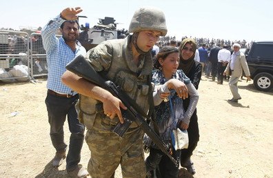 جندي تركي يساعد لاجئة سورية بعد عبورها الحدود التركية، 10 يونيو 2015