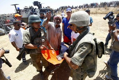 جنود أتراك يحملون لاجئة سورية إلى سيارة الإسعاف بعد عبورها الحدود التركية، 10 يونيو 2015