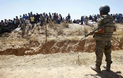  جندي تركي أثناء حراسة الحدود، بينما ينتظر السوريون لوسائل تنقلهم إلى داخل تركيا، 10 يونيو 2015