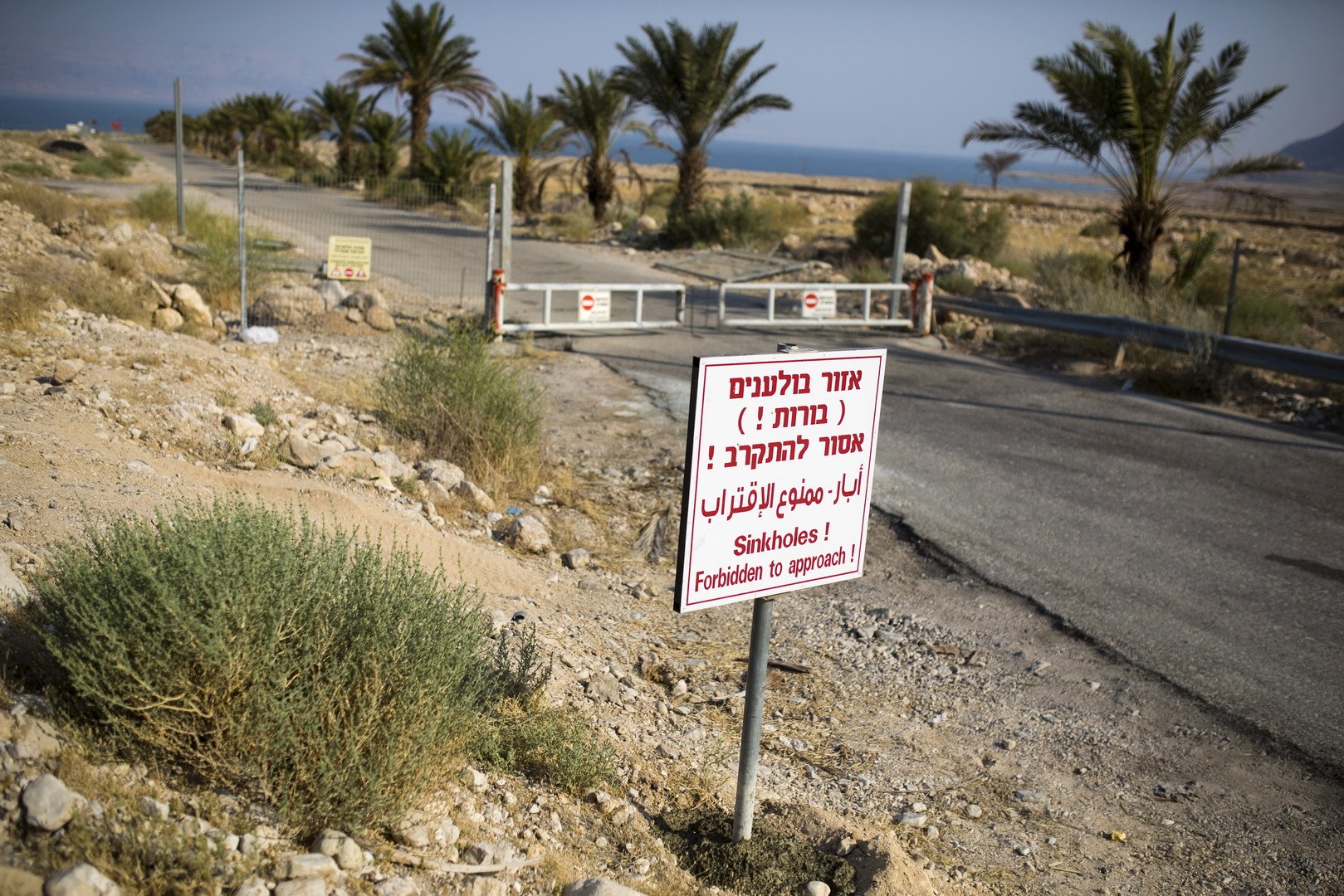 لافتة تحذر من الحفر الموجودة بمدخل أحد المنتجعات المهجورة على شاطئ البحر الميت، الجانب الإسرائيلي، 27 يوليو/تموز 