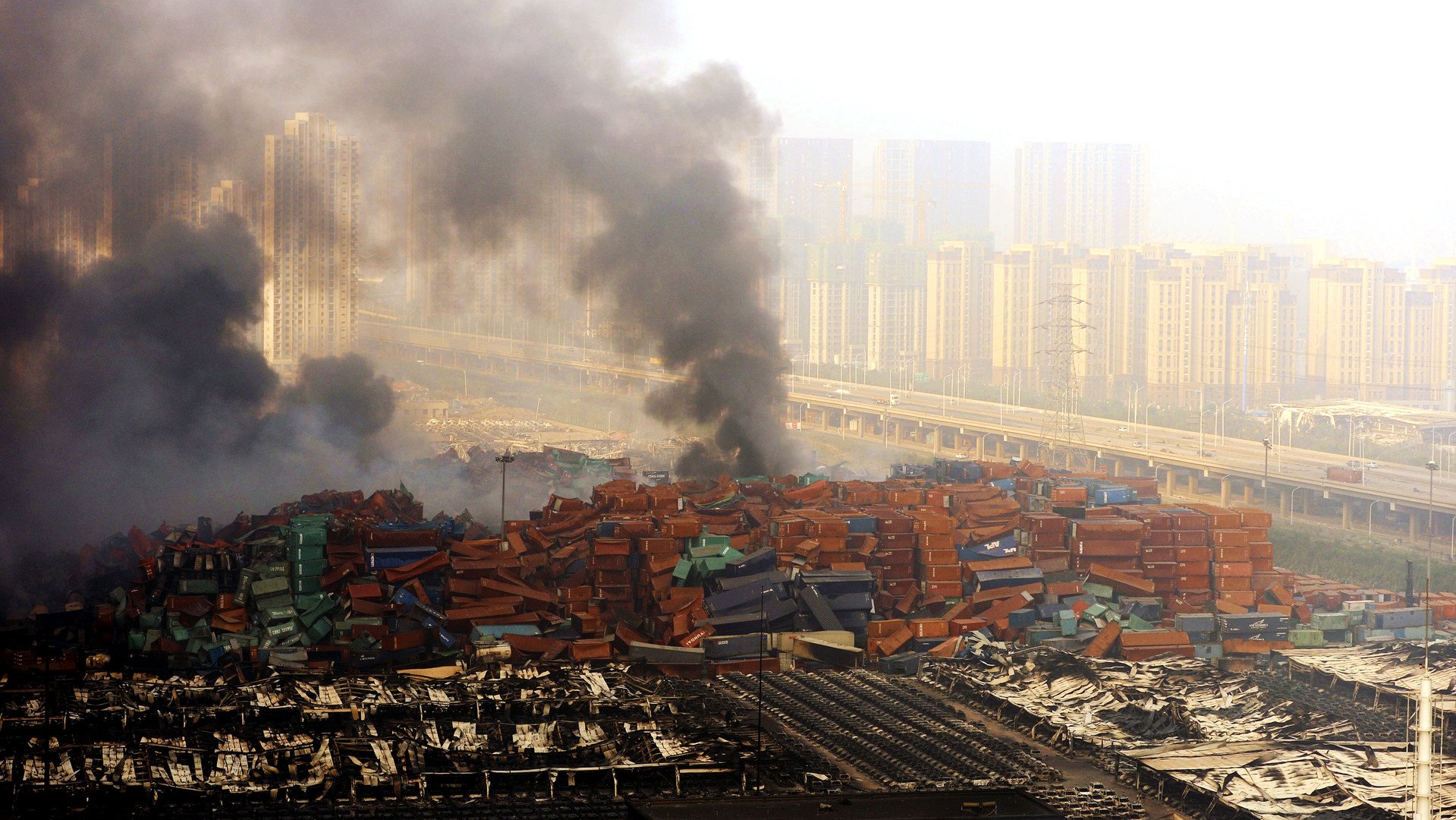 الدخان يتصاعد من حاويات النقل بعد حدوث انفجارين في منطقة صناعية، تيانجين-الصين.