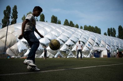 لاجئ يلعب كرة القدم أمام ملجأ للطوارئ في برلين