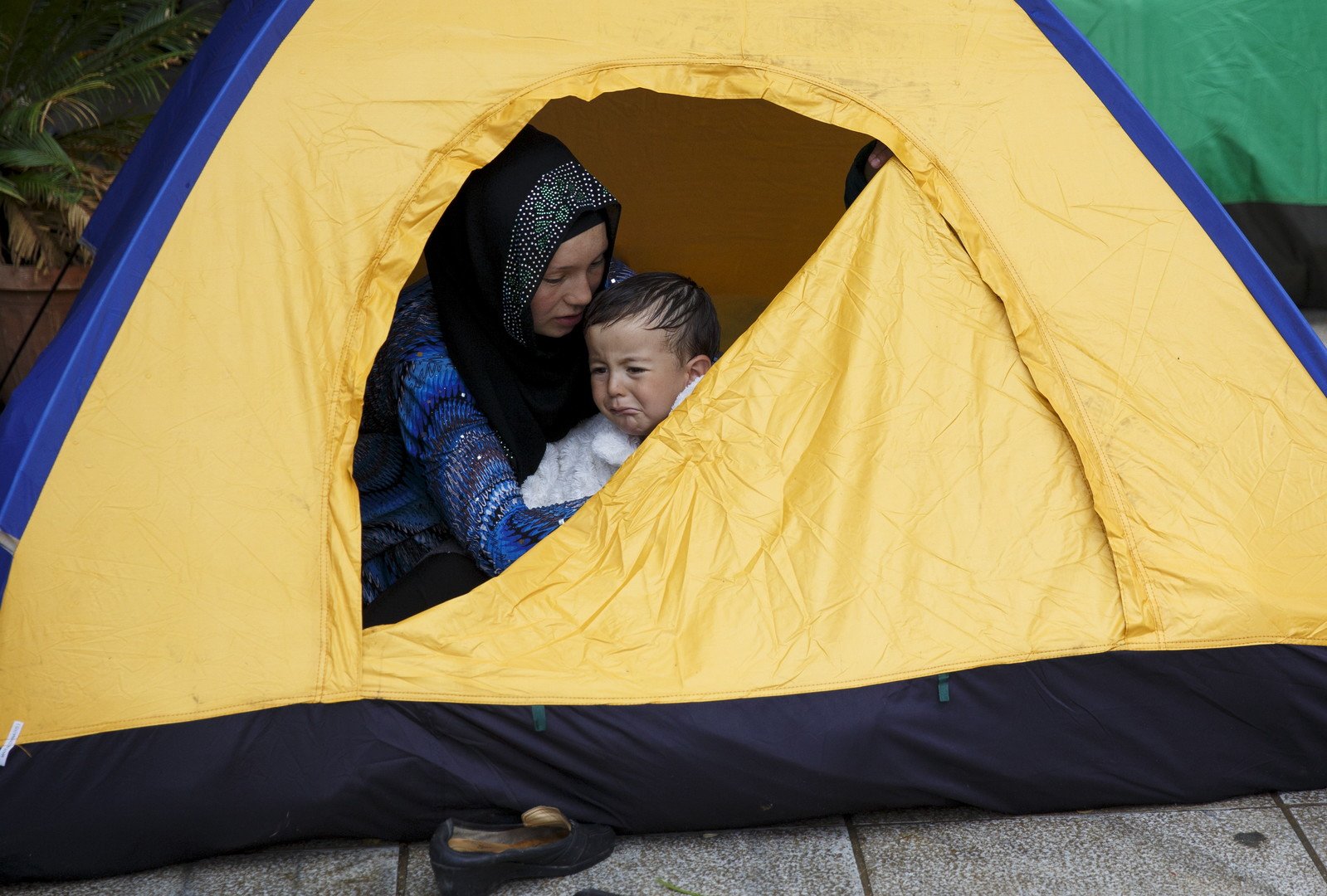 أم أفغانية تحتضن ابنها داخل خيمتهم في ساحة فيكتوريا بأثينا حيث يقبع مئات المهاجرين