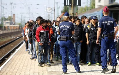 رجال من الشرطة الهنغارية يقفون على رصيف أثناء نزول مهاجرين من قطار وصل إلى أقرب محطة من الحدود النمساوية الهنغارية