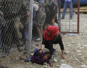 الشرطة تحاول منع المهاجرين من المرور من تحت السياج على الحدود قرب محطة القطار ببلدة جفجليجا بمقدونيا