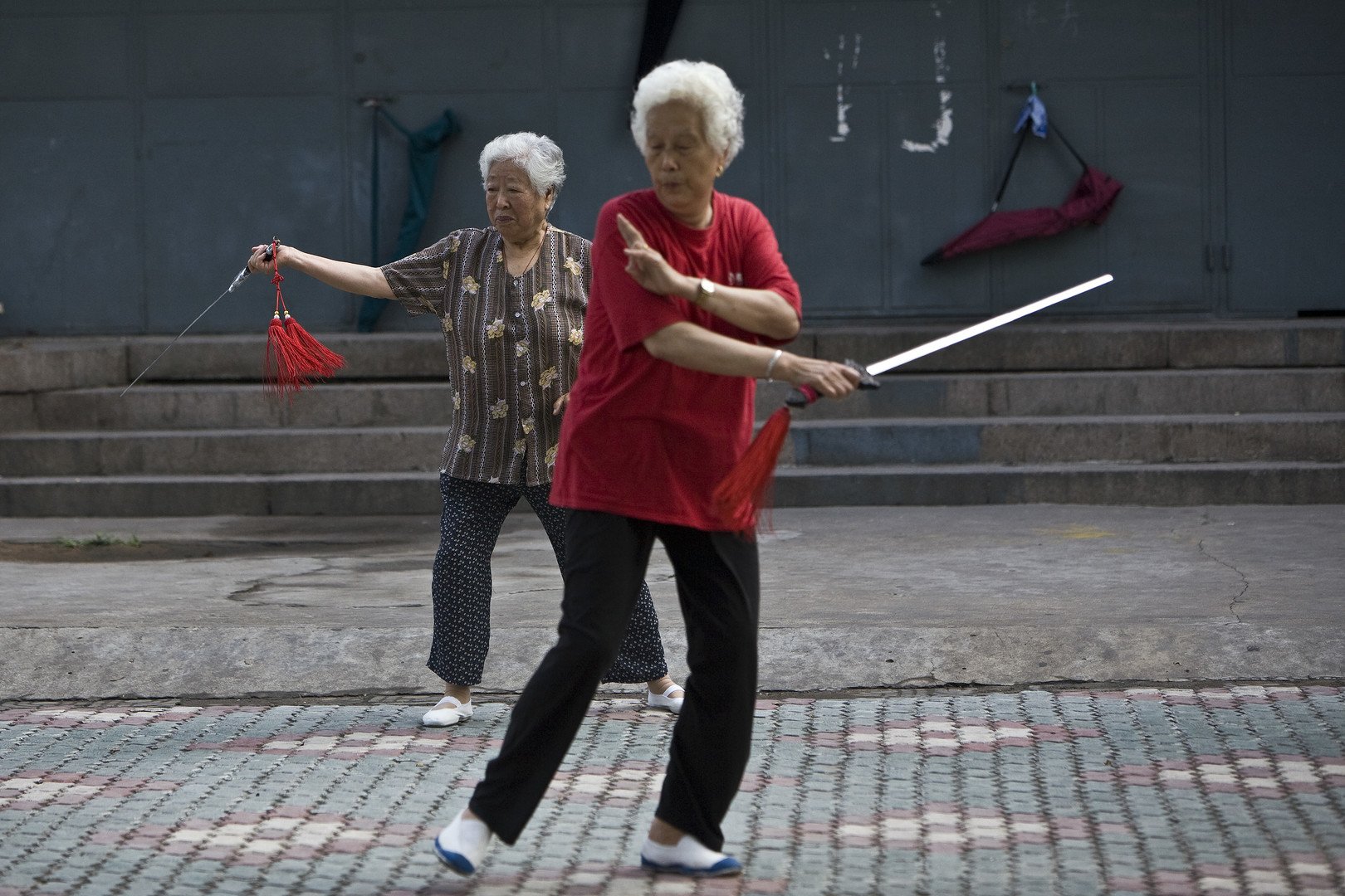 امرأة تمارس الرقص التقليدي باستخدام السيوف في تمارين الساعات الأولى من الصباح في حديقة كينغداو