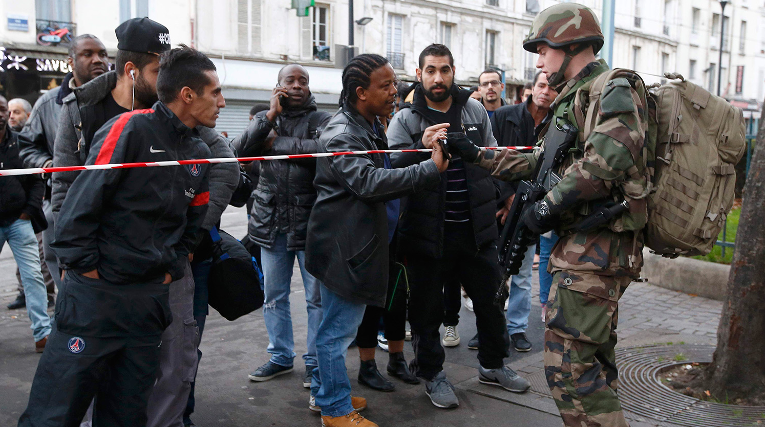 عسكري فرنسي يتأكد من الأوراق الثبوتية لرجل في منطقة أطلقت فيها النار