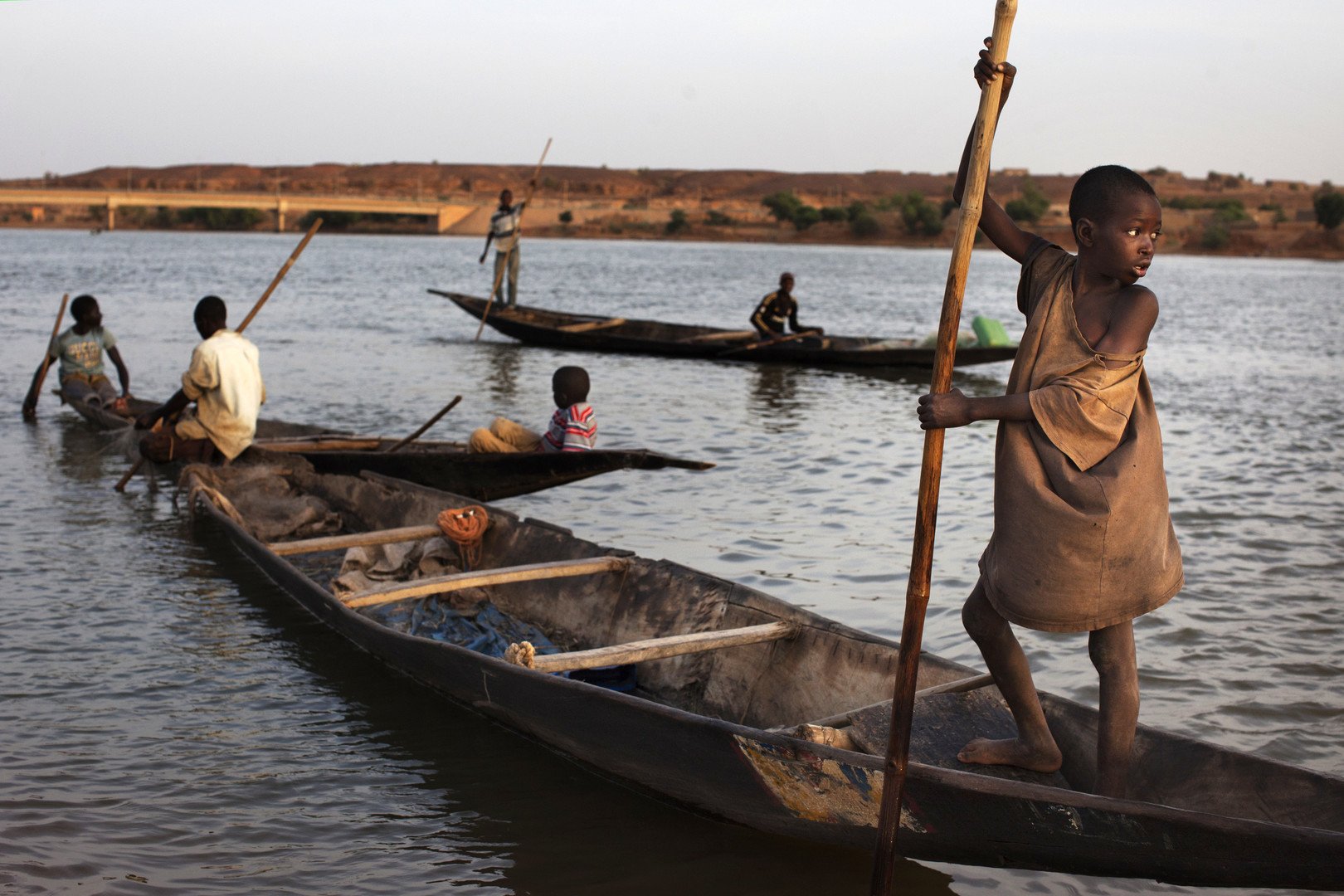 أولاد ورجال يصيدون السمك وهم يمتطون قواربهم في نهر النيجر