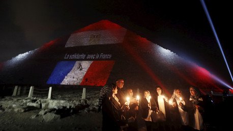 مصريون يشعلون شموعا على خلفية أضواء مسقطة بألوان العلم الفرنسي على هرم خوفو تخليدا لذكرى ضحايا الهجوم الإرهابي في باريس