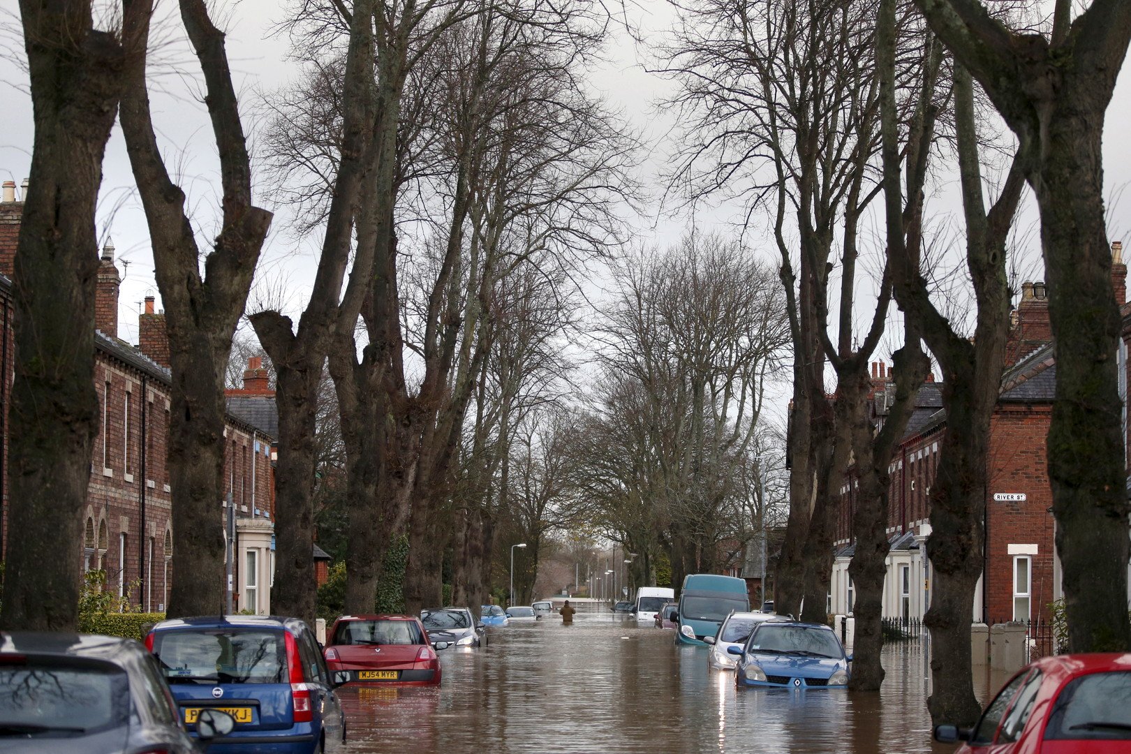 رجل يسير وسط مياه الفيضانات التي غمرت الشوارع والسيارات في مدينة كوكرماوث، شمال غرب انجلترا، 7 ديسمبر/ كانون الأول 2015