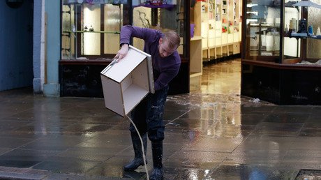 رجل يحاول التخلص من مياه الفيضانات التي غمرت أدراج مكتبه في مدينة كوكر ماوث، شمال غرب انجلترا، 7 ديسمبر/كانون الأول