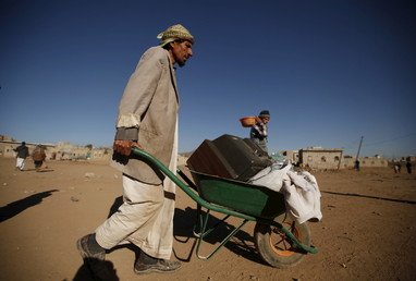 رجل يجر عربة يحمل عليها أثاث منزله، الذي تضرر بغارة جوية شنتها السعودية، على مشارف صنعاء