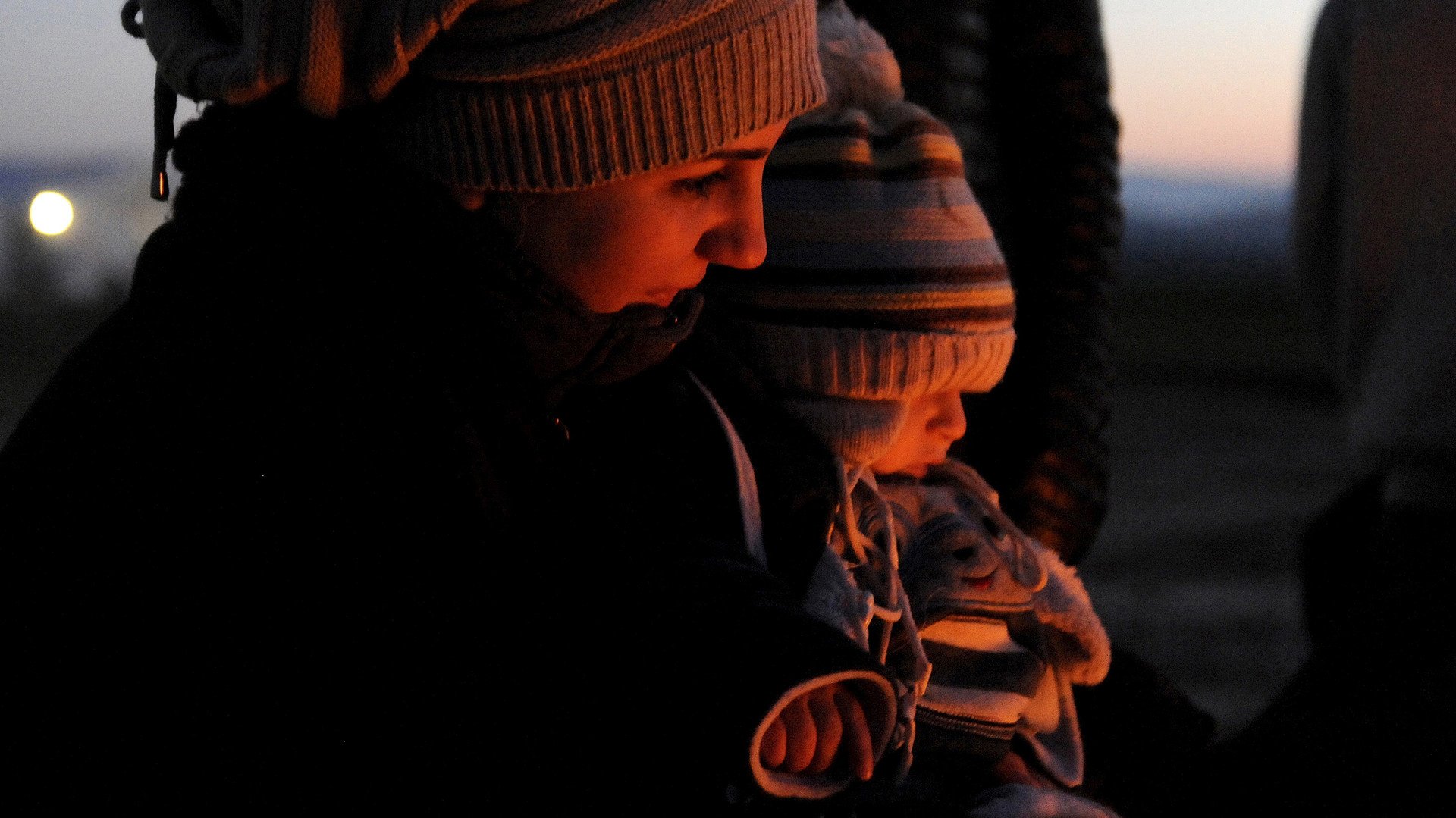 لاجئة سورية تحتضن ابنها وهي تجلس بقرب النار التي أشعلتها للتدفئة، في انتظار عبور الحدود اليونانية المقدونية، اليونان 21 يناير/كانون الثاني 2016