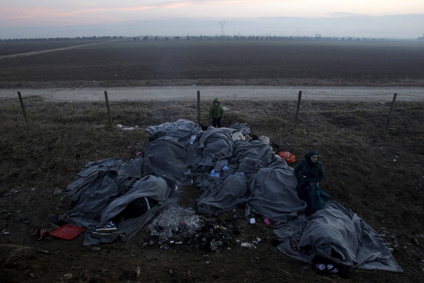 لاجئون ينامون في العراء محتمين فقط بالأغطية في انتظار عبور الحدود اليونانية المقدونية، بالقرب من قرية إيدوميني، 28 يناير/كانون الثاني 2016  