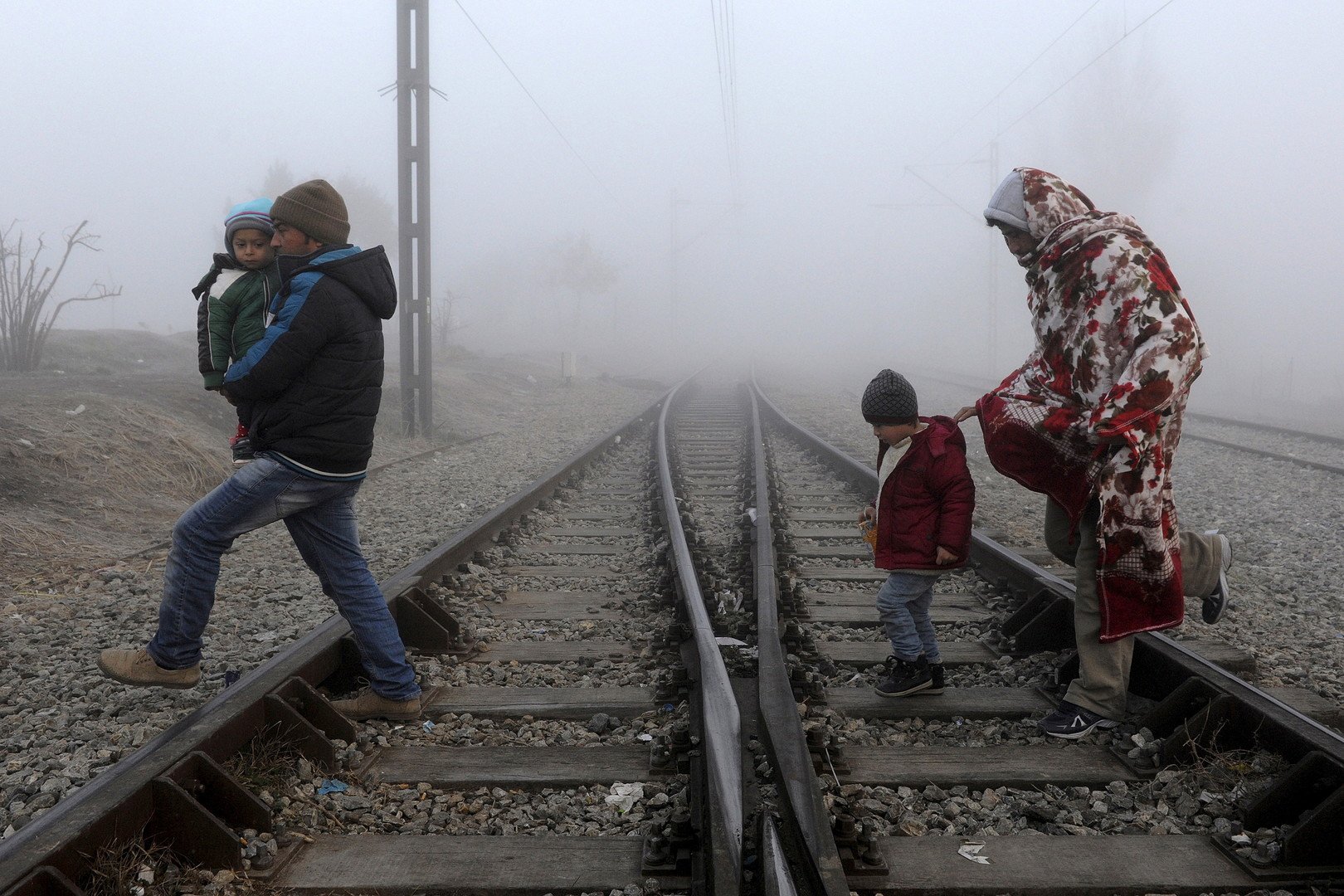 لاجئون يعبرون شريطا للقطارات في انتظار عبور الحدود اليونانية المقدونية، بالقرب من بلدة بوليكاسترو، 28 يناير/كانون الثاني 2016