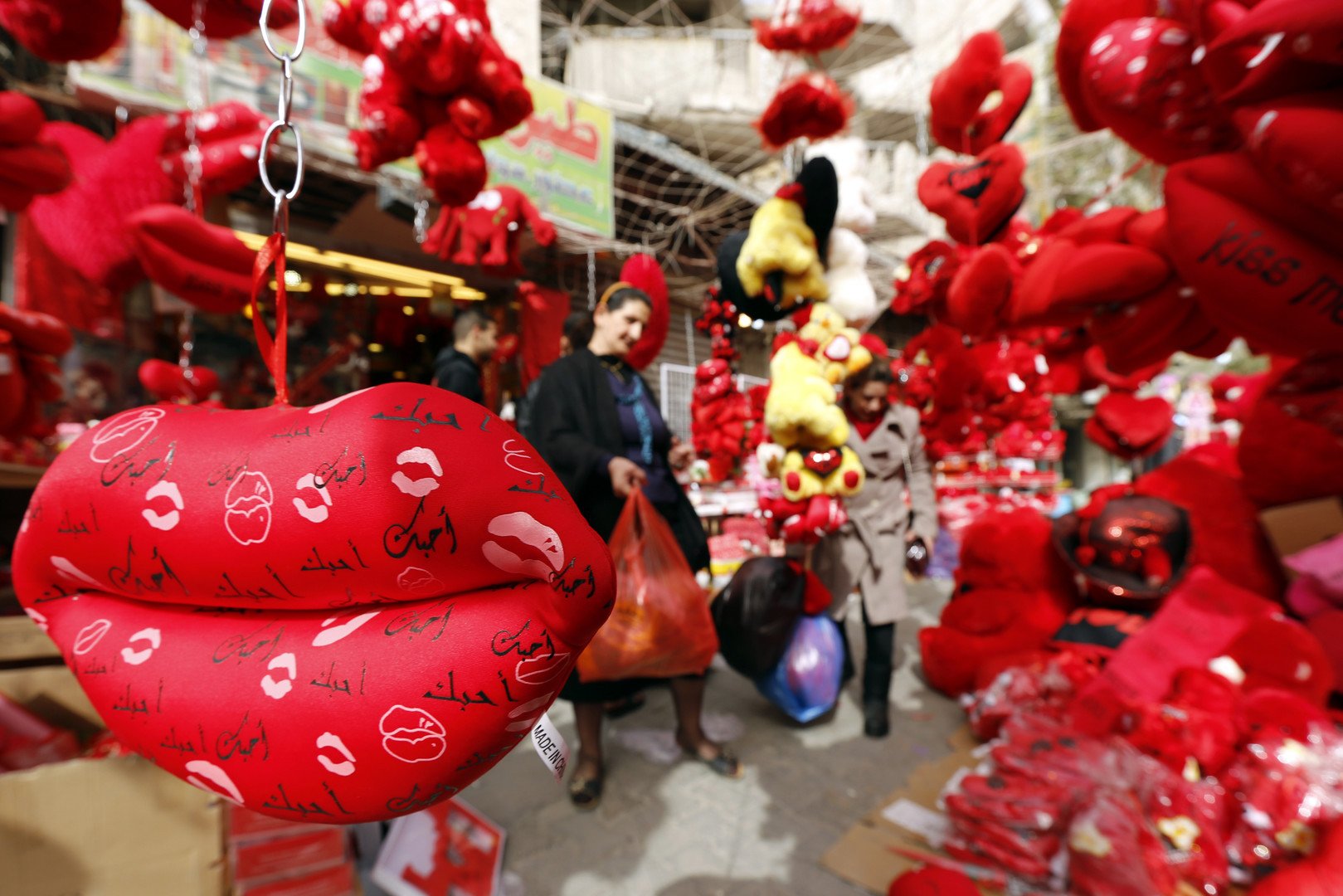 سيدة عراقية تتسوق داخل محل يعرض دمية الدب الشقي والوسادات الحمراء احتفالا بحلول مناسبة عيد الحب، منطقة الكرادة، 14 فبراير/شباط 2015  