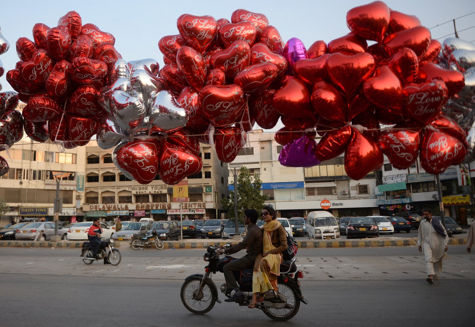 زوج باكستاني على دراجتهما النارية تحت كم هائل من البالونات المنصوبة فوق الشارع احتفالا بعيد الحب، كاراتشي، 14 فبراير/شباط 2014 