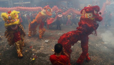 راقصون يؤدون عرضهم مرتدين أقنعة أسود اسطورية وسط الدخان المتصاعد من الألعاب النارية