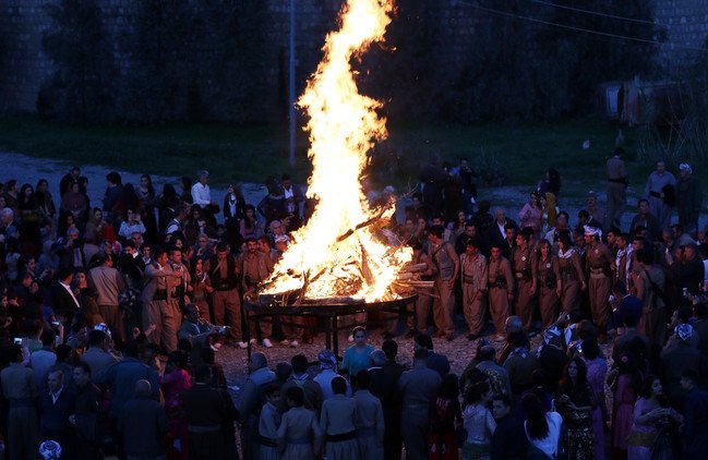 أعضاء من البيشمركة الإيرانية الكردية يحتفلون بعيد النوروز (رأس السنة الفارسية الجديدة) على أضواء النيران يوم 19 مارس/آذار من العام 2016