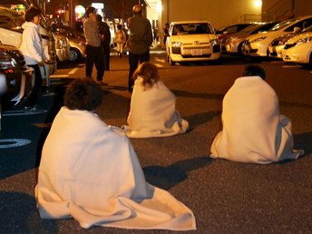 متضررون من الزلزال متلففون بالبطانيات يجلسون على الطريق بعد إجلائهم من فندق بعد وقوع الزلزال في كوماموتو بجنوب اليابان.